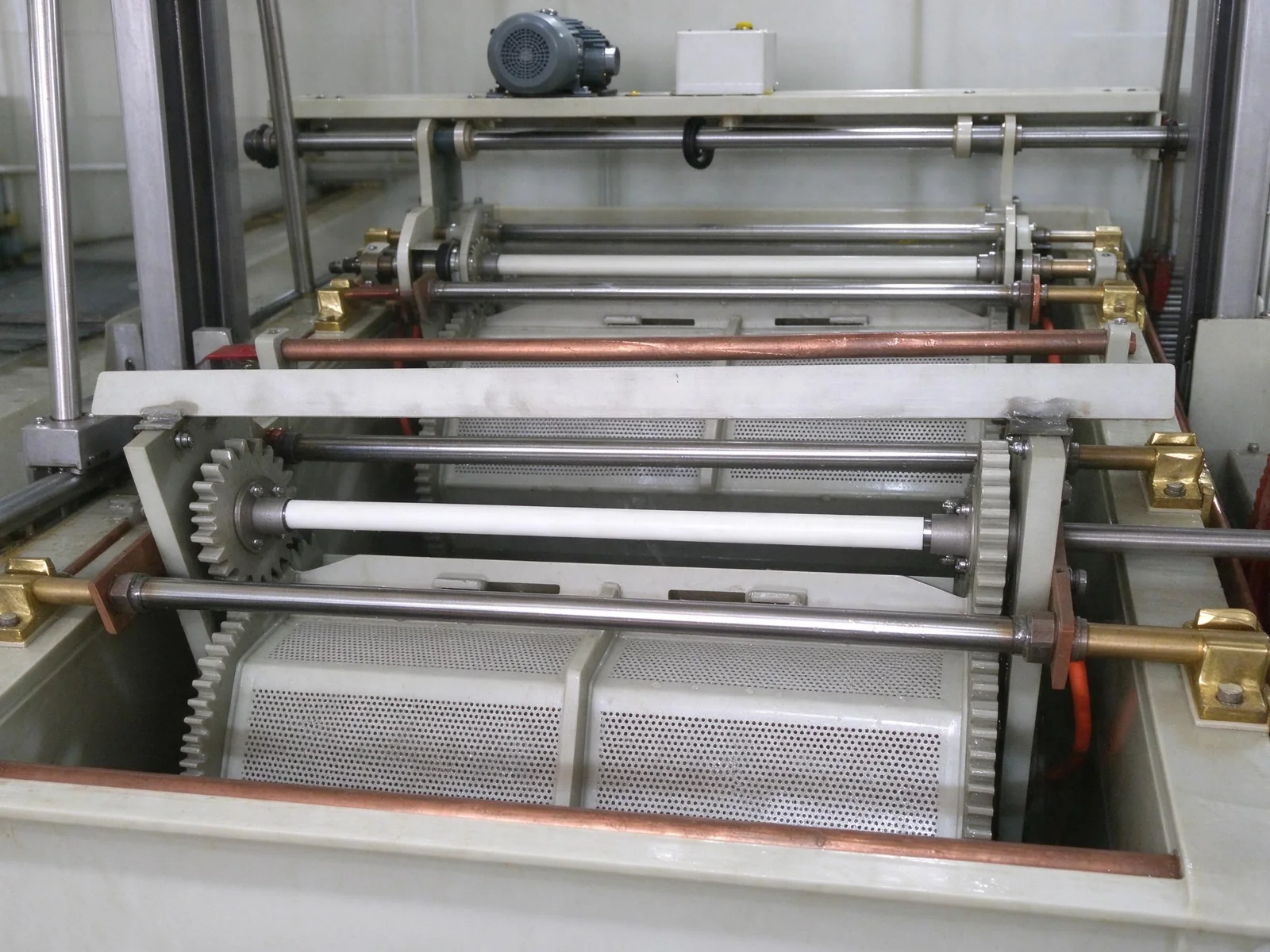 Industrial electroplating tank with lifting mechanism and perforated rollers.