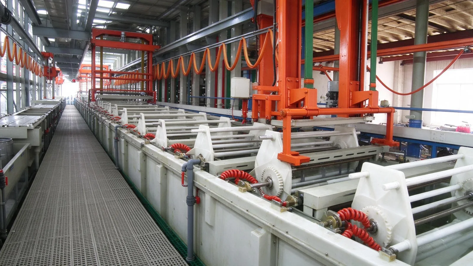 Industrial roll plating production line with long gold plating tanks and orange overhead cranes.