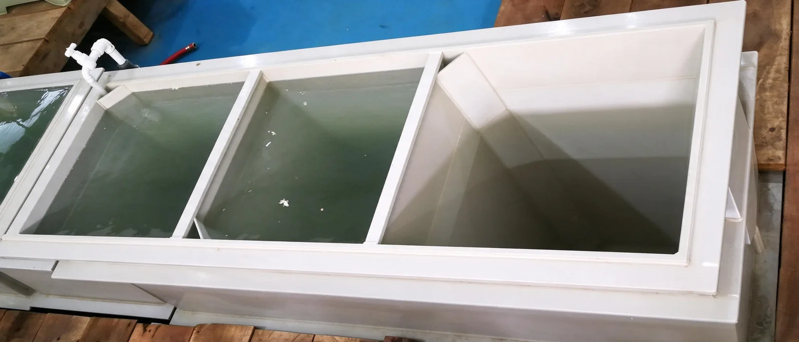 Industrial multi-stage white plastic water rinsing tank with internal partitions and faucet